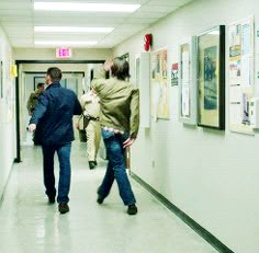 two people walking down a hallway with posters on the walls