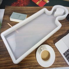 a desk with a laptop, coffee cup and other items on top of the table