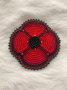 a red and black beaded brooch on white fur