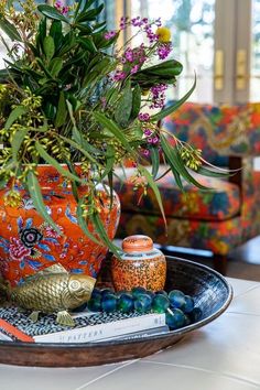 an orange vase filled with lots of flowers on top of a table next to a couch