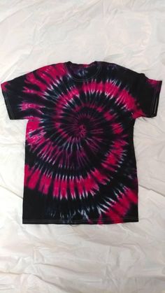 a red and black tie - dyed shirt laying on top of a white sheet