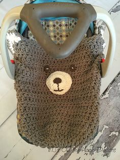 a crocheted teddy bear bag sitting on top of a wooden floor next to a stroller