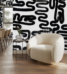 a white chair sitting in front of a black and white wall