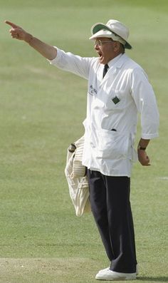 a man in white shirt and black pants standing on grass with his hand out to the side