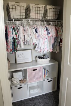 an organized closet with baby's clothes hanging on the rails and baskets above it