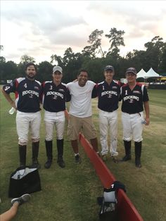 four men standing next to each other on a field