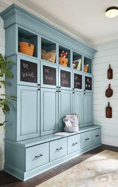 a room with blue cabinets and chalkboard writing on the doors, along with potted plants