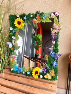 a wooden bench sitting next to a window covered in fake flowers and grass on top of it