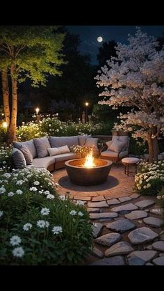 an outdoor fire pit surrounded by flowers and trees