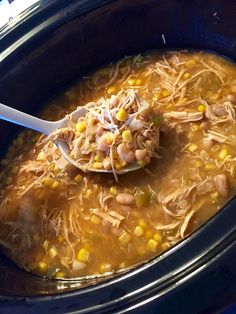 a spoon full of chicken and corn soup in a crock pot with the lid open