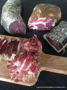 several pieces of raw meat on a wooden cutting board next to some other food items