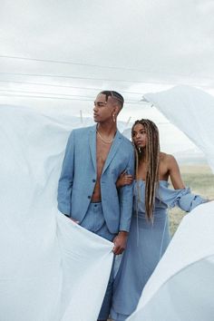 a man and woman standing next to each other in front of white sheeted material