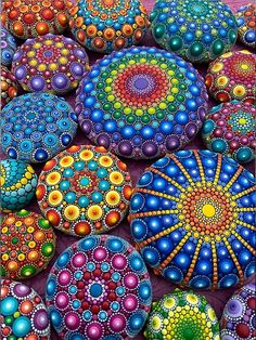 many colorful rocks are stacked together in the shape of an abstract flower and dots on them