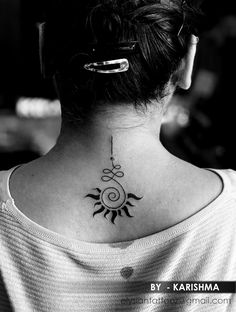 a woman's back neck with a sun and moon tattoo on her left side