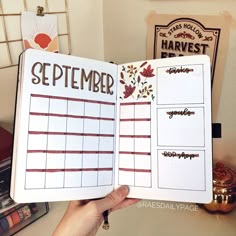 someone is holding up a planner with the month in front of them and writing on it