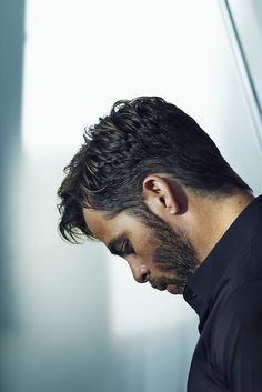 a man with long hair and beard wearing a black shirt looking down at his cell phone