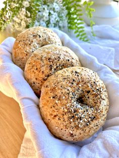 three bagels sitting on top of a white cloth next to some flowers and greenery