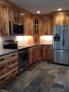 a kitchen with wood cabinets, stainless steel appliances and tile flooring is pictured in this image