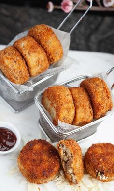 three tins filled with food sitting on top of a white table next to dipping sauce