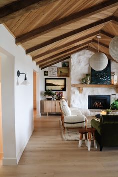 a living room filled with furniture and a fire place under a wooden beamed ceiling