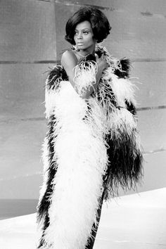 a black and white photo of a woman in an animal - print dress with feathers