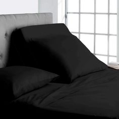 a bed with black sheets and pillows on it