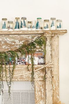 an old fireplace with jars and greenery on top