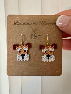 a pair of beaded earrings with a dog on it's ear is shown