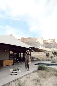 a woman standing in front of a tent next to a camera set up on a tripod