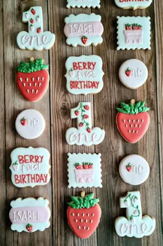 decorated cookies are arranged on a wooden table with the words happy birthday and one strawberry