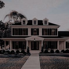 a large white house with lots of windows and black shutters on the front porch