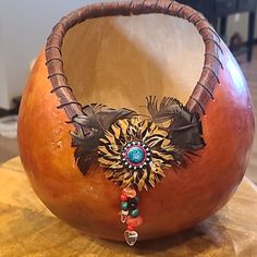 an orange vase with a decorative decoration on it's side sitting on a table