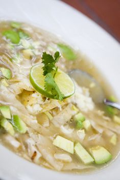 a close up of a bowl of soup with broth and avocado garnish