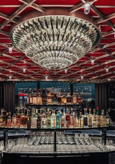 a bar with lots of bottles and glasses on top of the counter under a chandelier