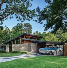 a blue truck parked in front of a house next to a lush green yard and trees