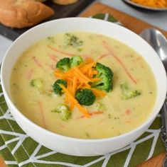 a white bowl filled with broccoli and carrots next to a slice of bread