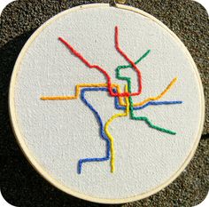 a cross stitch pattern on a white hoop with colored thread in the shape of a map