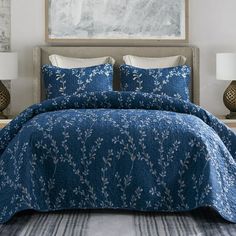 a bed with blue and white comforters in a bedroom next to two nightstands