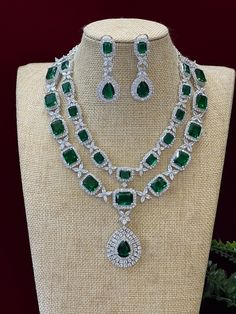 This beautiful American diamond double layer mala/necklace features emerald green stones and is perfect for bridal wear. It's sure to provide the perfect touch of elegance and sophistication to any look. With its long length, it's sure to draw attention. Look stunning in this gorgeous American diamond double-layer mala necklace that comes with matching emerald green earrings! The 2.5 inch earrings are clip-backed for balance, adding a touch of elegance to your look. Make any occasion extra speci Emerald Green Stone, Emerald Green Earrings, Green Stones, Mala Necklace, Green Earrings, American Diamond, Green Stone, Bridal Wear, Long Length