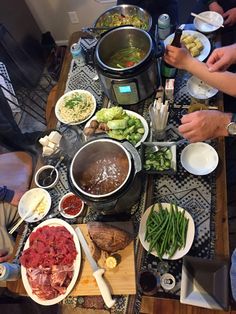 several people are gathered around a table full of food