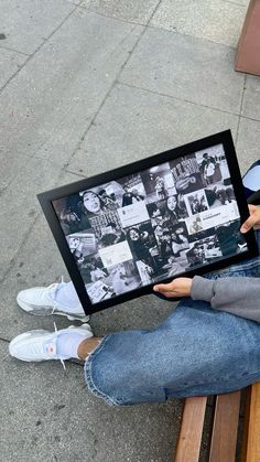 a person sitting on a bench holding up a framed photo