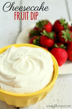 a yellow bowl filled with cream cheesecake fruit dip next to strawberries on a plate