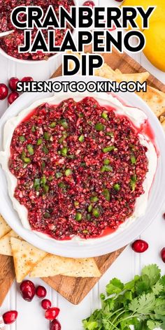 cranberry jalapeno dip in a white bowl surrounded by crackers and limes