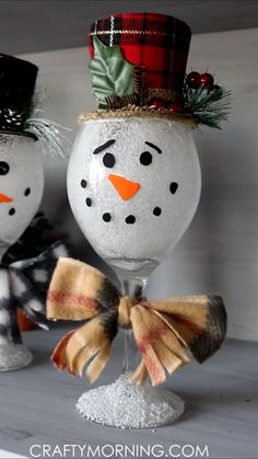 two snowmen are sitting next to each other in wine glasses with bows on their heads