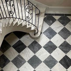 a black and white checkered tile floor next to a staircase with wrought iron railings