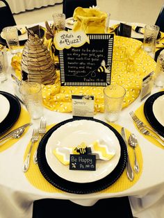 a table set for a bee themed birthday party with yellow napkins and black plates