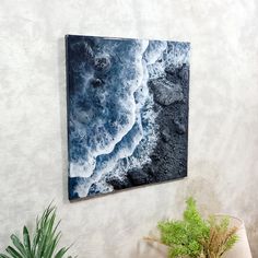 a painting hanging on the wall next to a potted plant