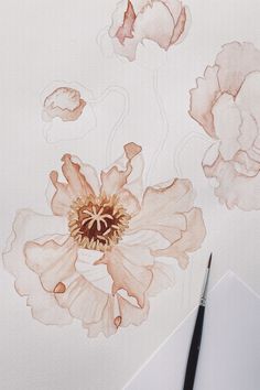 a drawing of a flower with watercolors on paper next to a pencil and marker