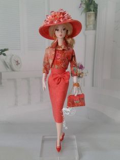 a barbie doll wearing a red dress and hat with a handbag in her left hand