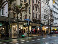 people are standing on the sidewalk in front of shops